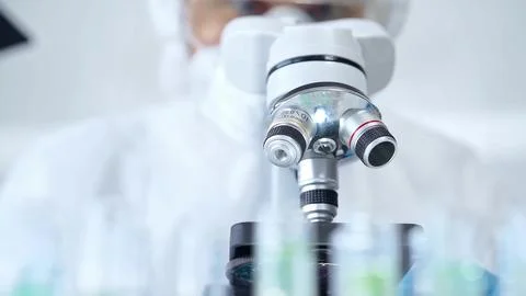 Professional scientist in protective gear is using microscope in a laboratory 스톡 사진