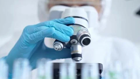 Professional scientist in protective gear is using microscope in a laboratory Stock-Fotos