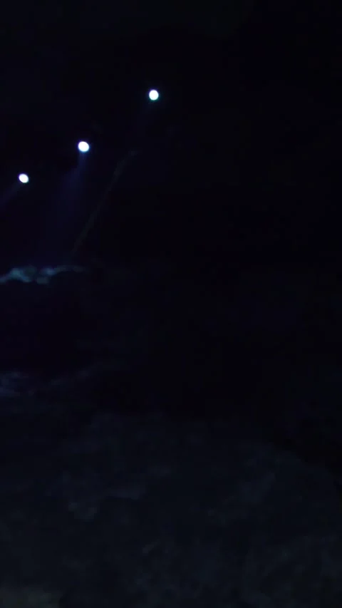 Professional scuba divers with flashlights swimming through a dark, mysterious Stock Footage 332001684