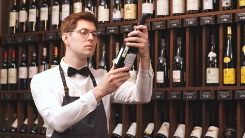 Professional seller selects a bottle of wine for You depending on the country of Stock Photos