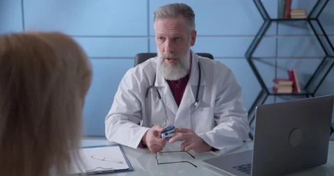 Professional serious focused middle aged hoary physician in medical coat sitting Stock Footage 148050819