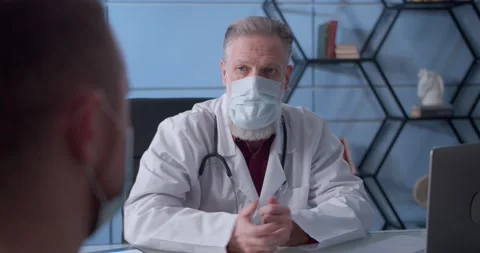 Professional serious focused middle aged hoary physician in medical coat and Stock Footage 148374801