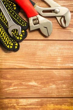 Professional set of tools and work gloves for plumbers on a vintage wooden bo Stock Photos