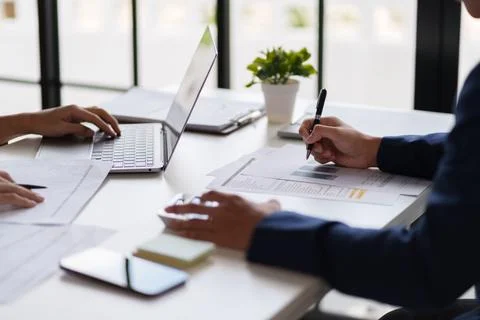 Professional setting featuring two individuals working at a table. They are.. Stock Photos