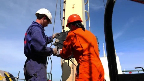 Professional ship workers connect vessel radar to rope Stock Footage 113455178