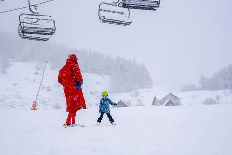 Professional ski instructor is teaching a child to ski on a mountain slope Stock Photos