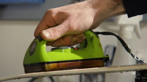 Professional skier applying glide wax on skis with help of waxing iron Stock Footage 129115729