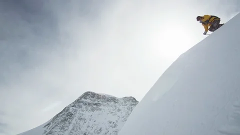Professional skier cruising down the cliffs of a snowy mountain Stock Footage 113219928
