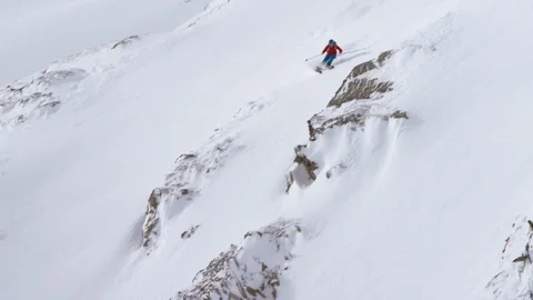 Professional skier making turns against rocks while skiing down the snowy slope Stock Footage 116741963