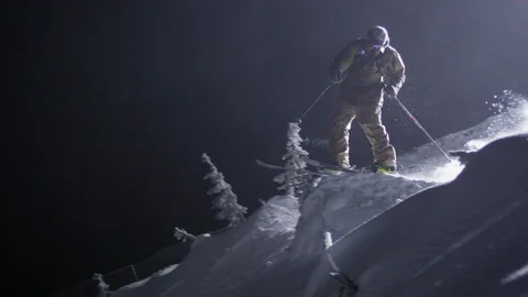 Professional skier spinning while jumping down the snowy slope at night Stock Footage 116738418