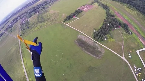 Professional skydiver on parachute fly down to green field for landing. Extreme Stock Footage 70532447