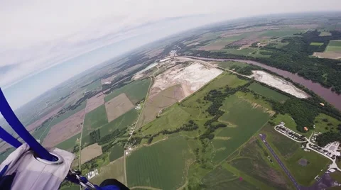 Professional skydiver parachuting in cloudness sky above green flatland. Sport Video stock 67236309