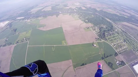 Professional skydiver parachuting in cloudy sky above green flatland. Landscape Видео 67237604