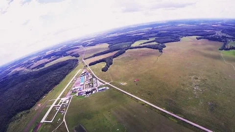 Professional skydiver parachuting, fly over green field in sunny day. Landscape Stock Footage 70533043