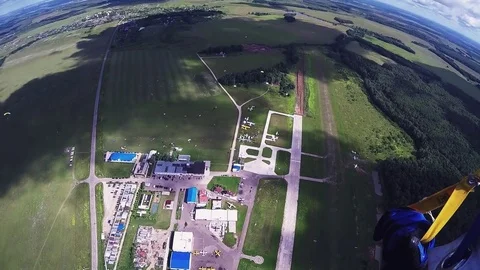 Professional skydiver parachuting, fly over green field in sunny day. Nature Видео 70533082
