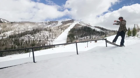 Professional snowboarder does a trick on snowboarding rail on snow clad region Stock Footage 116786206