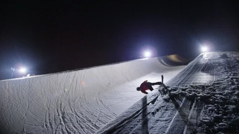Professional snowboarder performs a flip on half pipe at night Stock Footage 116786460