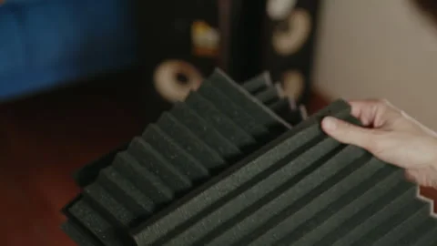 Professional sound engineer handling dark gray acoustic foam panels, preparing Video stock 312330086