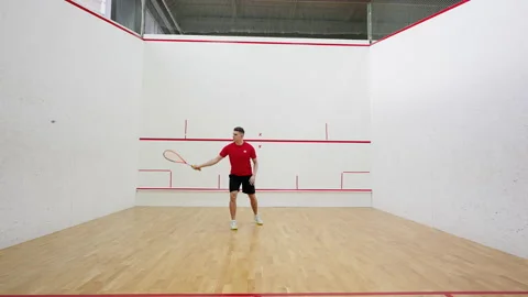 Professional squash player hits rubber ball with racket Stock Footage 220978016