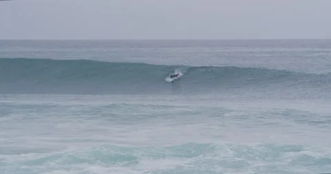Professional surfer preparing to ride big waves in wavy ocean during cloudy day Stock Footage 156011146