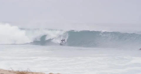 Professional surfer riding down fast ocean wave during cloudy day, Nazare Video stock 156009193