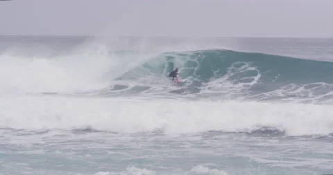 Professional surfer riding inside big barrel wave during cloudy day, Nazare Video stock 156007708