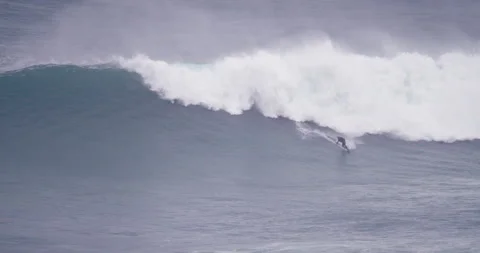 Professional surfer surfing down on huge ocean wave during cloudy day Stock Footage 157723299