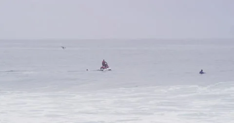 Professional surfers trying to get on board behind jet ski driver on cloudy day Stock Footage 156009599