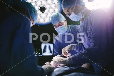 Professional surgeons performing surgery in operating room Stock Photos