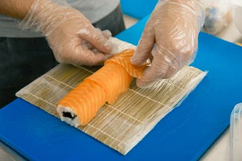 Professional sushi chef preparing roll at commercial kitchen. Cook puts the s Stock Photos
