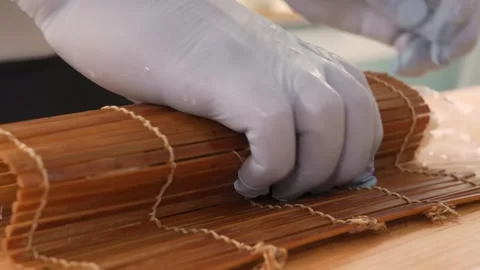 Professional Sushi Chef Rolling Fresh Maki Roll Using a Traditional Bamboo Mat Stock Footage 333502139