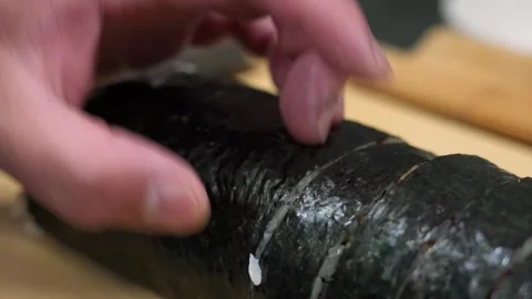 Professional Sushi Chef Slicing Fresh Nori Roll on a Wooden Board Stock Footage 333573286