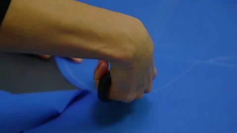 Professional tailor cuts clothes template on blue cloth Stock Footage 136400513