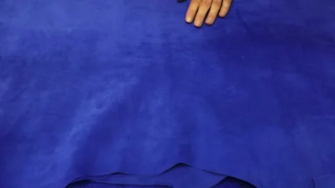 Professional tailor hands turn over fabric of blue colour Stock Footage 136400521