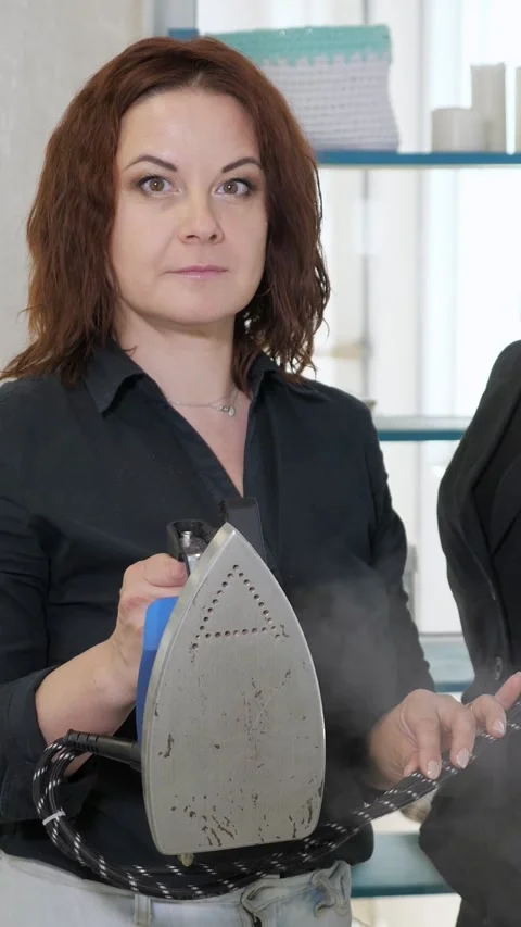 Professional tailor steaming a black jacket in a textile workshop, a woman with Stock Footage 340841839