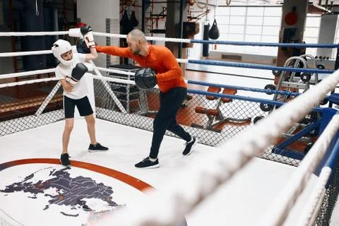 Professional talented trainer learning a boy to protect himself during boxing Stock Photos