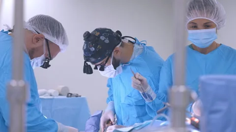 A professional team of doctors and surgeons performs surgery on the patient Stock Footage 255136910