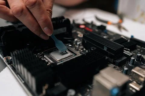 Professional technician applying thermal paste to CPU of computer motherboard Foto stock