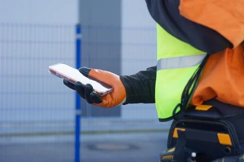 Professional technician uses a mobile device for digital project management.. Stock Photos