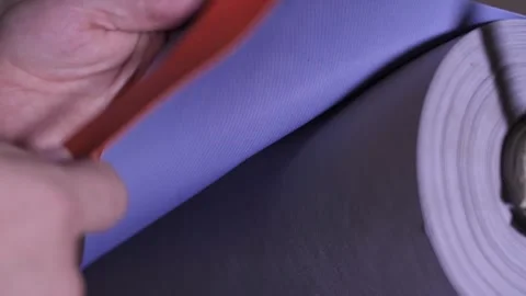 Professional textile worker demonstrated two-sided purple and orange fabric. Video stock 313815353