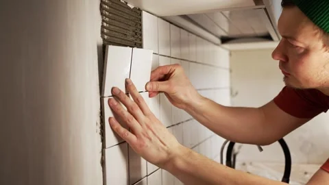 Professional tiler installing ceramic tiles on kitchen backsplash wall during Stock Footage 344568008