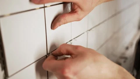 Professional tiler installing ceramic wall tiles and using plastic spacers to Stock Footage 344565967
