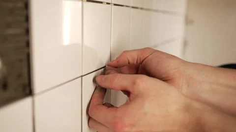 Professional tiler installing white ceramic tiles on a wall during home Stock Footage 344565030