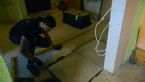 Professional tiler laying large ceramic tiles on a concrete floor Stock Footage 346492185