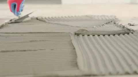 Professional tiler spreads tile adhesive with a notched trowel installing tiles Stock Footage 341134562