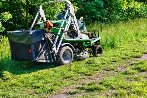 A professional tractor mower driven by a public utility worker climbs up the  Foto stock