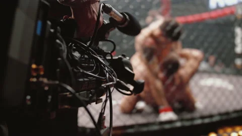 Professional TV camera shoots that MMA fighters spar in octagonal ring cage Stock Footage 149321663