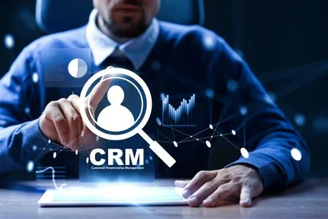 Professional using CRM software on a tablet in a dark office setting Stock Photos