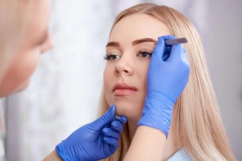 Professional using forceps for plucking eyebrows Stock Photos