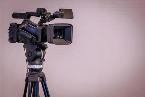 Professional video camera mounted on a tripod with a focus lens and microph.. 库存照片